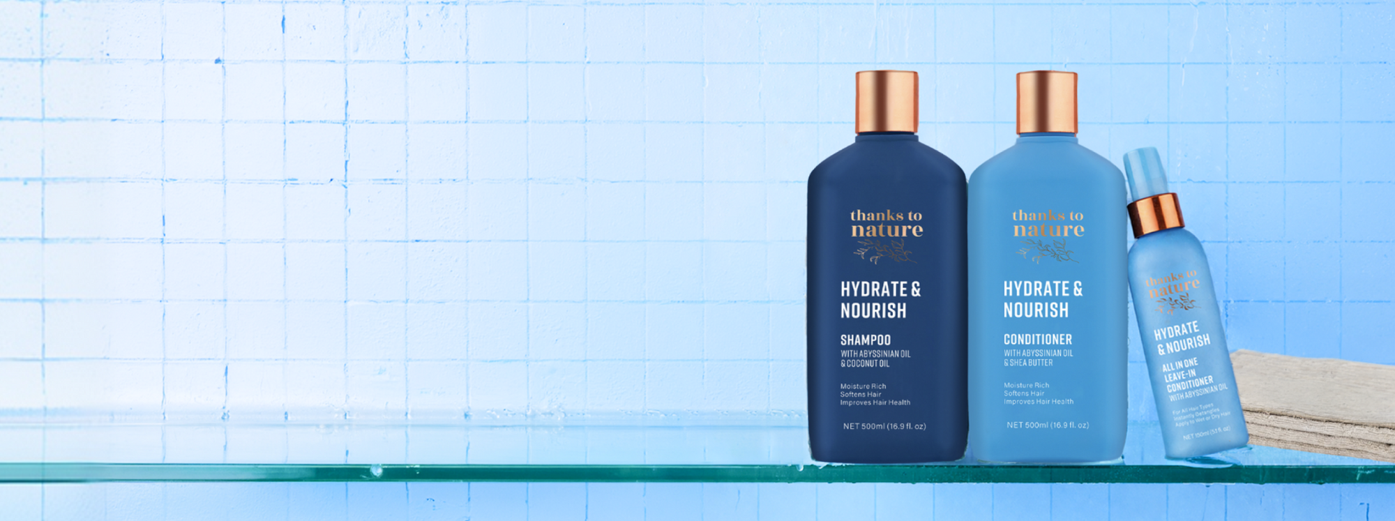 Three bottles of 'Sheaven by Nature' hair care products on a glass shelf with a blue gradient background.