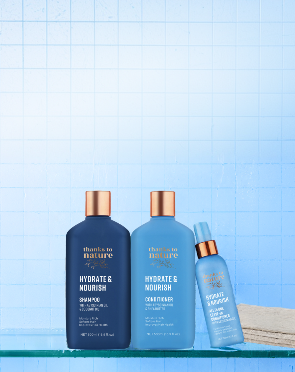 Three bottles of 'Thanks to Nature Hydrate & Nourish' shampoo, conditioner, and serum on a blue grid background.
