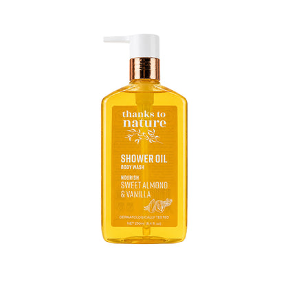 A 250ml bottle of 'thanks to nature' Shower Oil Body Wash in Sweet Almond & Vanilla scent. The product is a translucent amber-yellow bottle with a white pump dispenser and a metallic bronze neck collar, set against a solid white background.