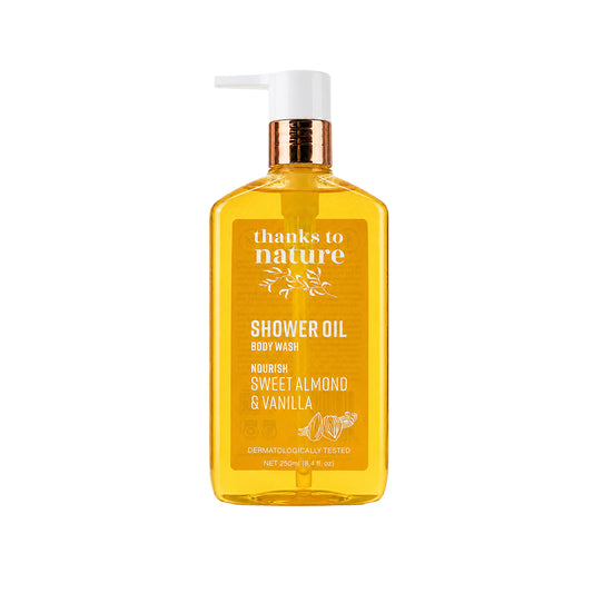 A 250ml bottle of 'thanks to nature' Shower Oil Body Wash in Sweet Almond & Vanilla scent. The product is a translucent amber-yellow bottle with a white pump dispenser and a metallic bronze neck collar, set against a solid white background.