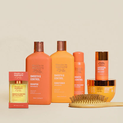 Thanks to Nature Smooth and Control Collection of hair care products including bottles and a brush on a beige background